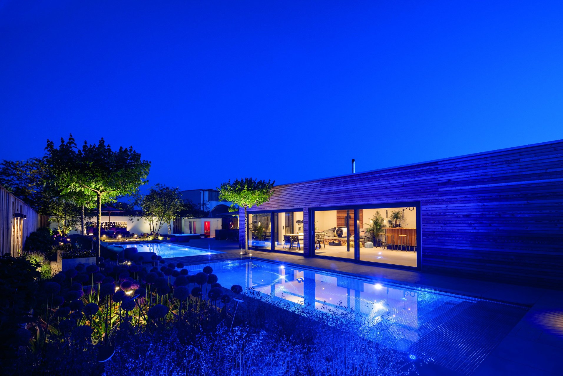 Beleuchteter Swimmingpool mit moderner Gartenplanung – RivieraPool Hannover