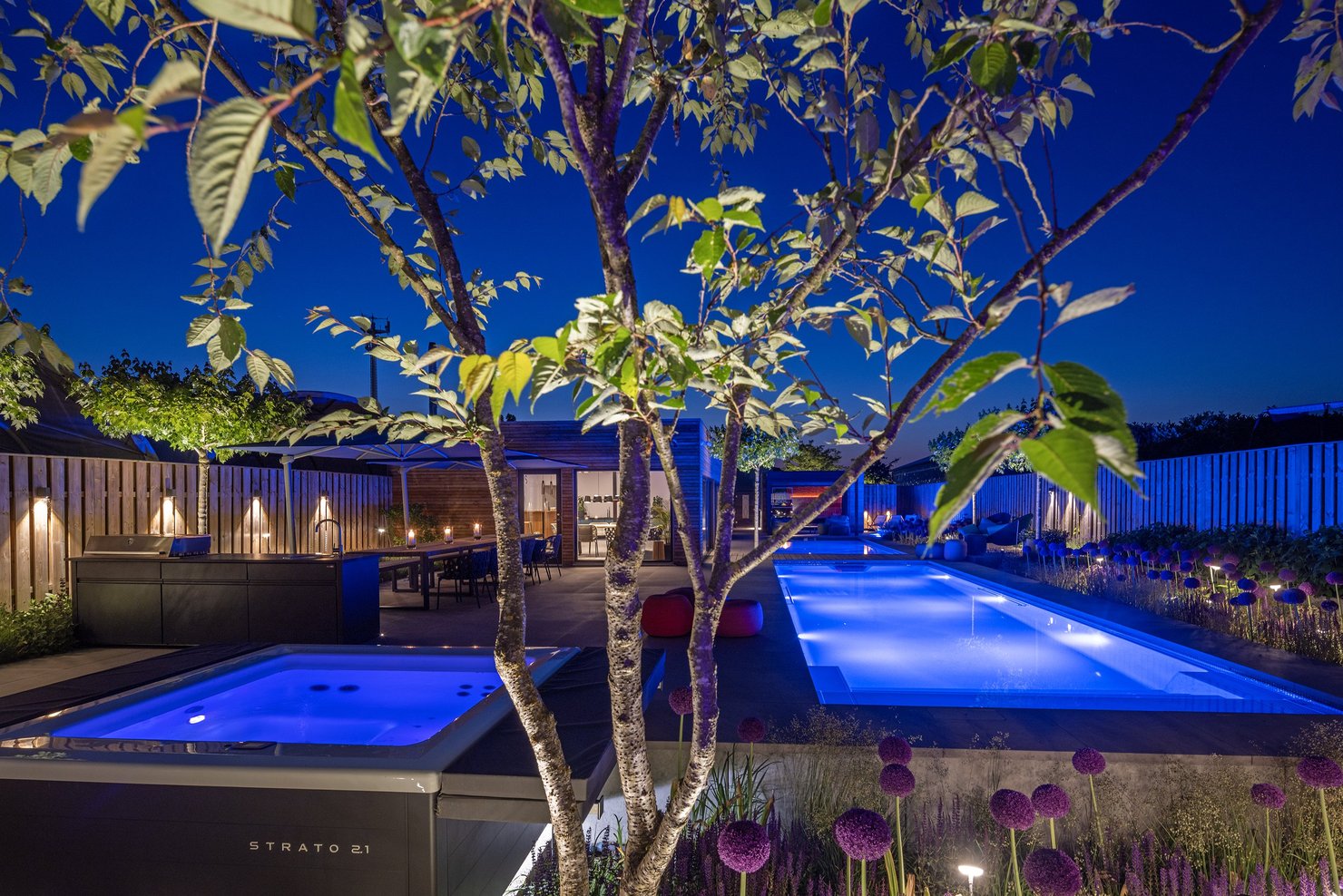 RivieraPool D·Line Linear RS 1175, 370 × 1175 cm in Granicite Steingrau mit LED-RGB-Beleuchtung neben Whirlpool Strato – Ausstellung Hannover